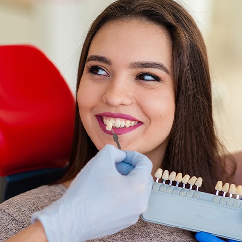 Woman's smile compared with tooth color chart