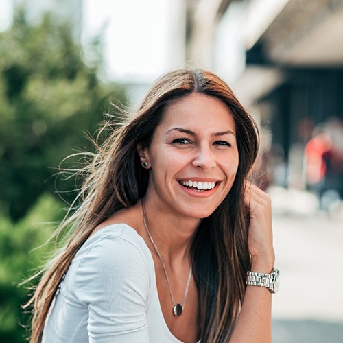 A young woman sitting outside and smiling with a beautiful smile in North Dallas