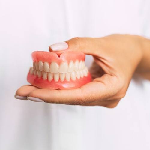 dentist holding dentures in North Dallas