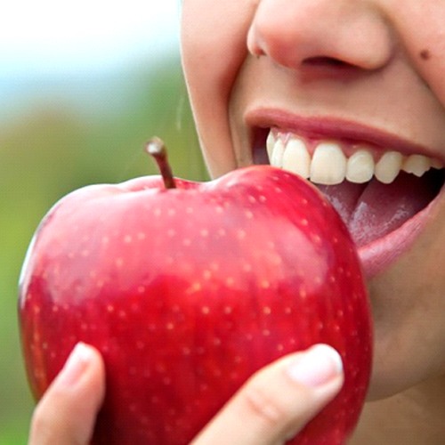 close up person about to eat an apple