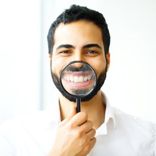 man in white dress shirt holding magnifying glass to his smile