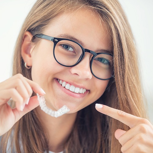 Smiling teen points to her Invisalign in North Dallas