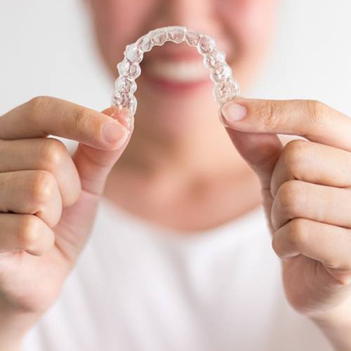 Closeup of Invisalign in North Dallas, smiling woman in background.