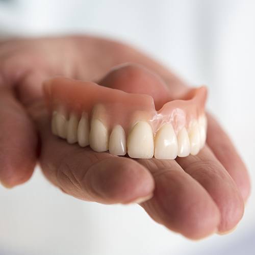 Hand holding full denture