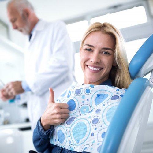 woman giving thumbs up in dental chair 