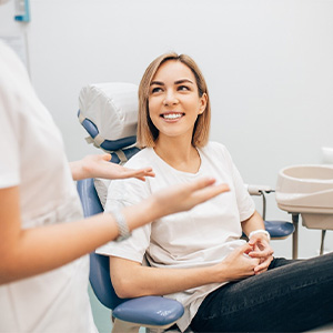 woman talking with dentist to prevent dental emergencies in Dallas