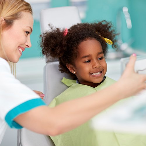 Child in dental office looking at smile in mirror