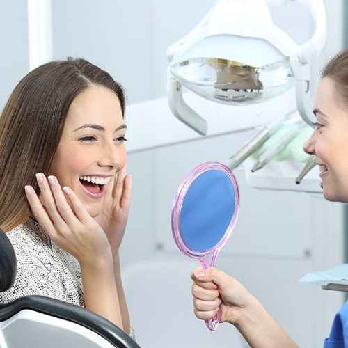 Smiling woman admiring her new veneers in North Dallas 