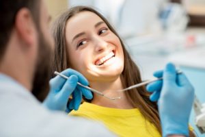 Woman smiling while getting a checkup from her North Dallas dentist