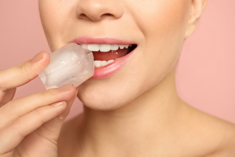 Closeup of woman holding up ice cube to her mouth
