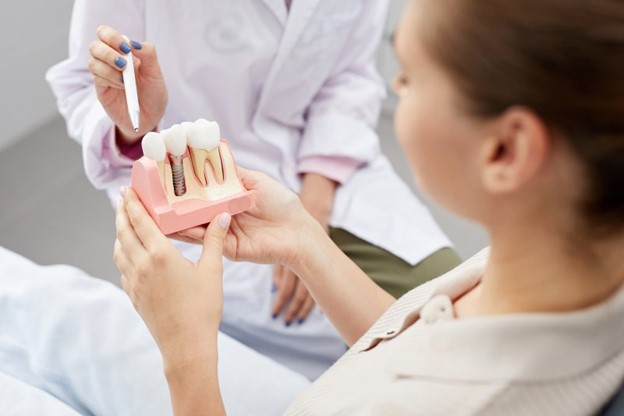 Patient at the dentist’s office holding a model of dental implants.