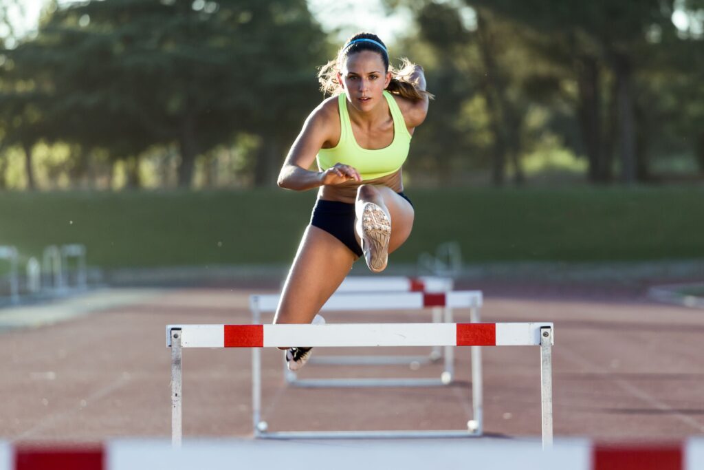 Woman in yellow sports bra hurdling